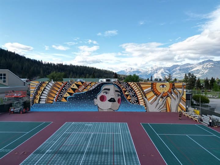 Freshly resurfaced tennis and pickleball courts at the Jasper Activity Centre, with a large hand-painted mural and the Rocky Mountains behind